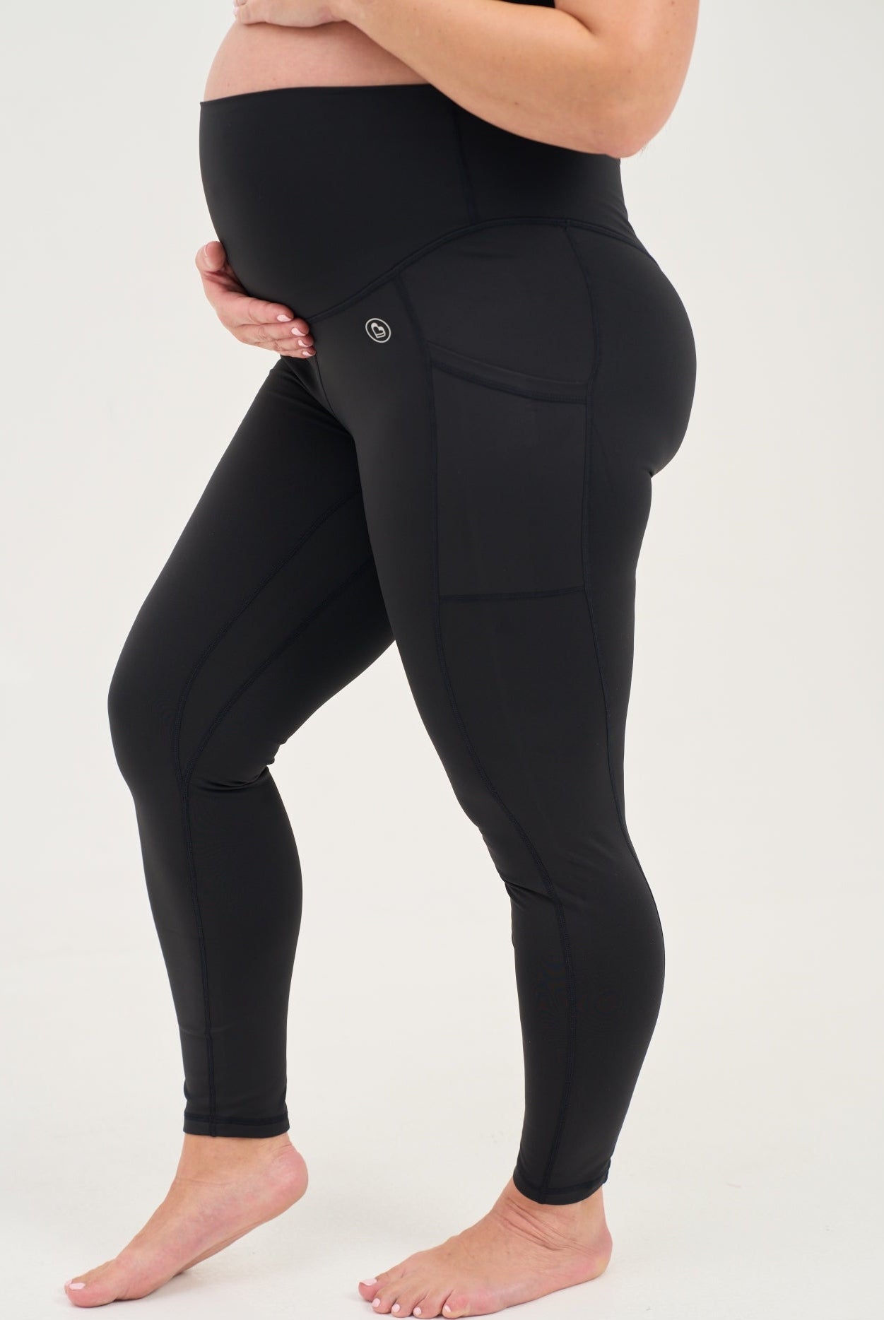 Mum wearing black maternity leggings with pockets on a white background