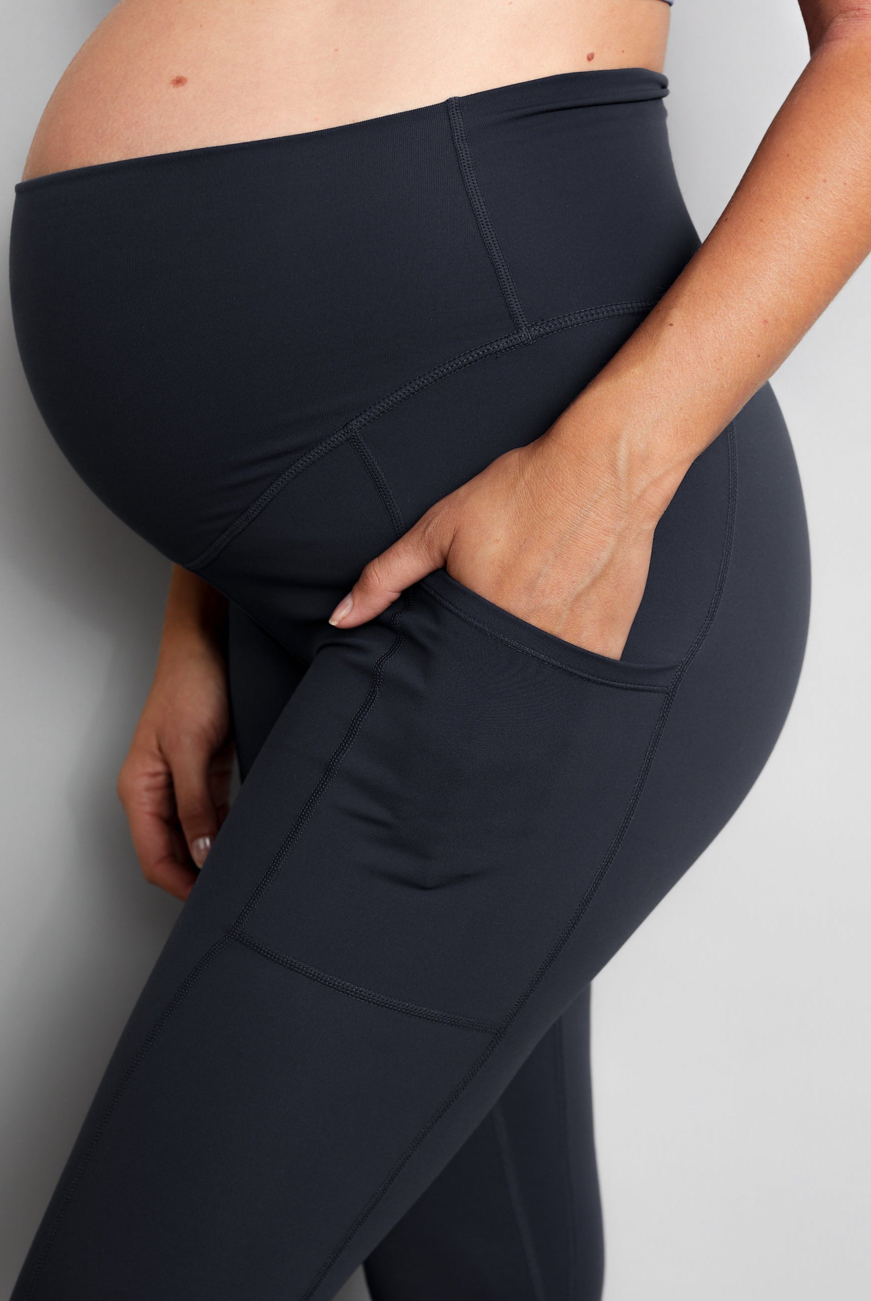 Person wearing black maternity leggings against a grey background