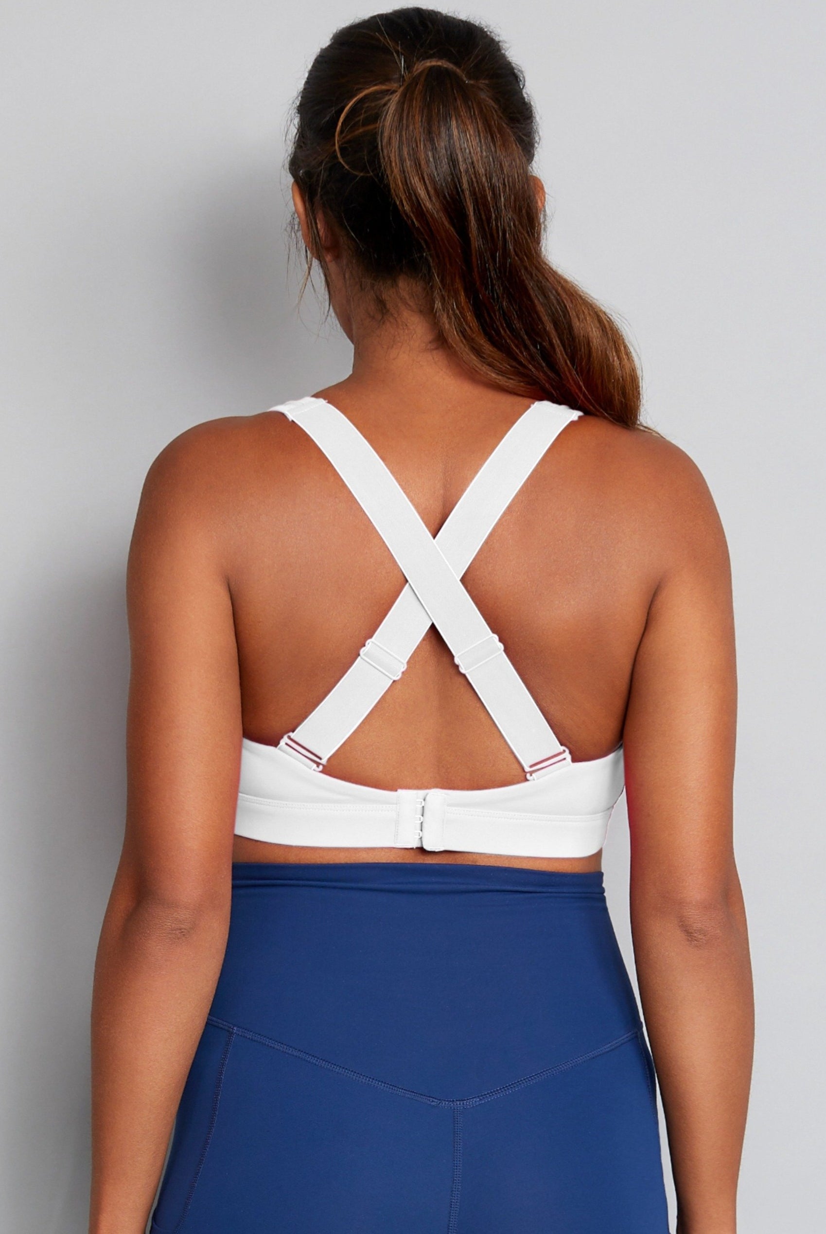 Back straps of white nursing sports bra with blue leggings.