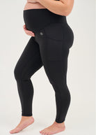 Mum wearing black maternity leggings with pockets on a white background