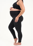 Mum wearing black maternity leggings with pockets on a white background