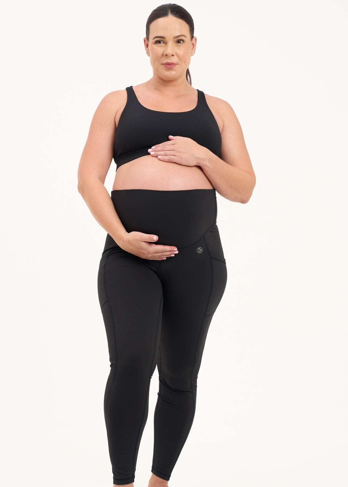 Mum wearing black maternity leggings with pockets on a white background