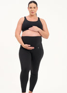 Mum wearing black maternity leggings with pockets on a white background