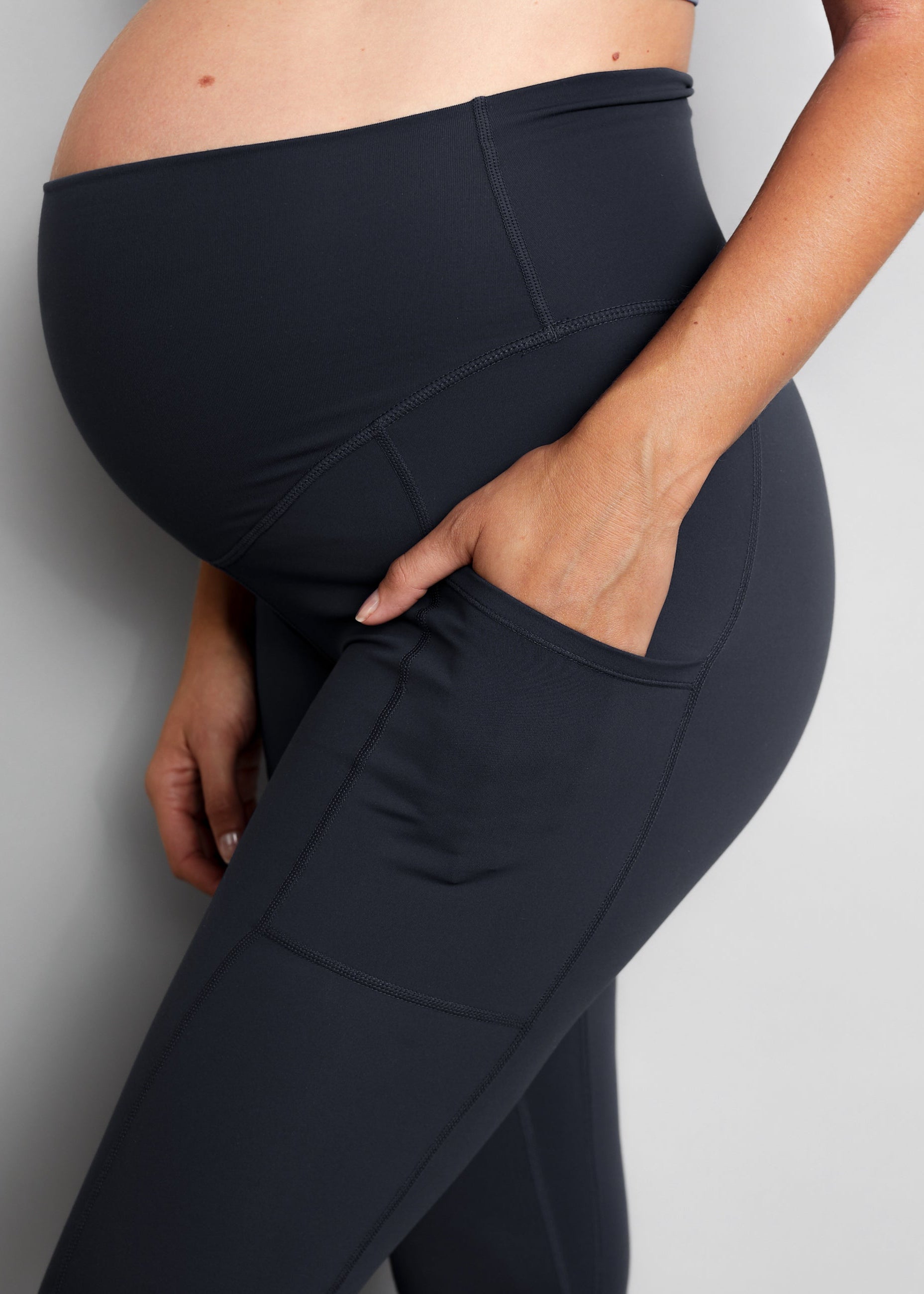 Person wearing black maternity leggings against a grey background