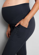 Person wearing black maternity leggings against a grey background