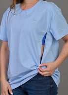 Woman wearing a light blue t-shirt and dark blue jeans against a gray background